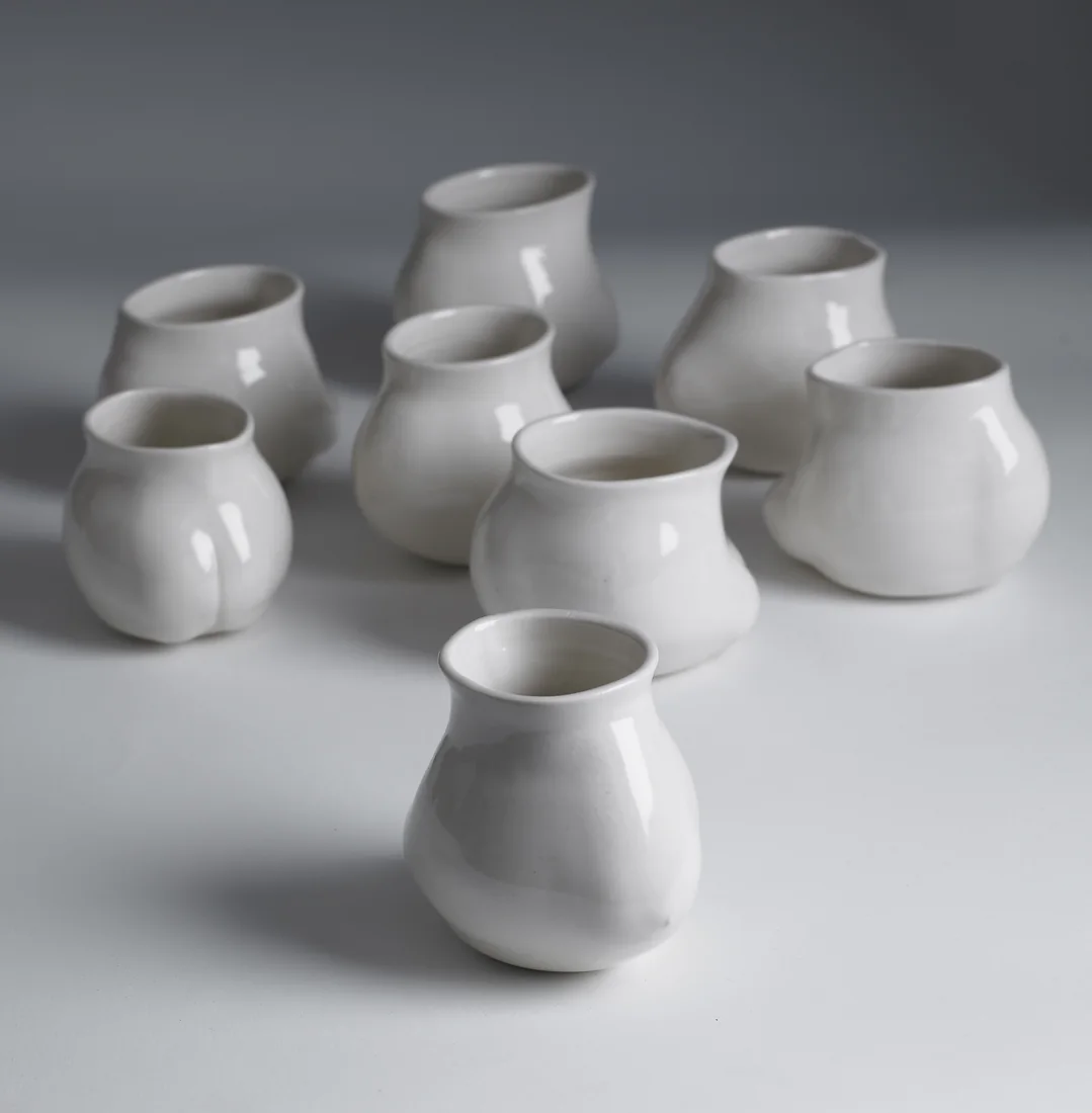 A group of rounded unglazed white porcelain mugs.